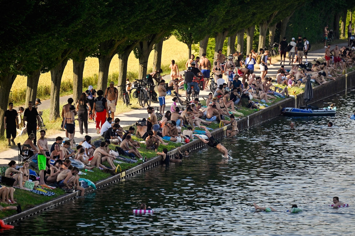 People sit at the side of the Dortmund-Ems Canal in Dortmund, western Germany on June 26, 2026 during a heatwave in Europe. A heatwave sweeping Europe was starting to peak in Germany on June 25, 2026, with several open-air events cancelled and temperatures expected to top 40C through the weekend. Large parts of the country are already under "severe to extreme heat stress" with temperatures soaring to around 37C, the German Weather Service (DWD) said. (Photo by Ina FASSBENDER / AFP)